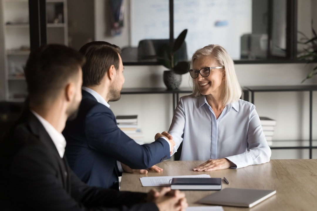 Positive,Confident,Younger,And,Older,Business,Partners,Shaking,Hands,On